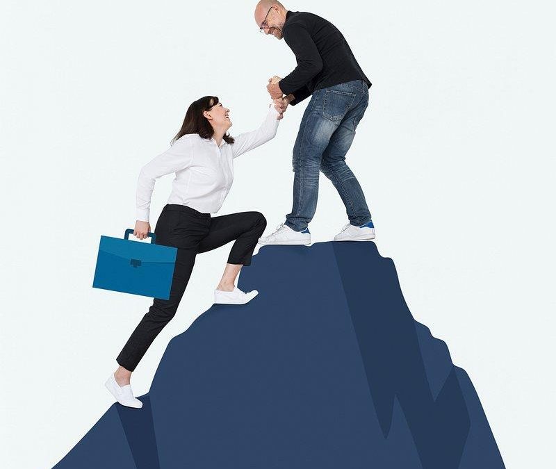Représentation d'une personne en difficulté en bas d'une motagne et une personne en haut qui aide la première personne à monter sur la montagne par une main tendu